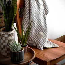 Load image into Gallery viewer, Natural Hardy Houndstooth Cotton Throw Blanket draped on back of chair next to plants
