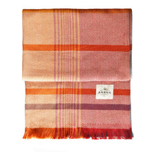 Load image into Gallery viewer, Orange and red patterned blanket and a visible brand label on a white background