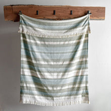 Load image into Gallery viewer, Striped blanket hanging from a wooden rack against a white wall