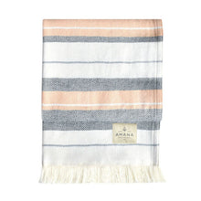 Load image into Gallery viewer, Folded striped blanket with orange, black and white pattern on a white background, featuring the Amana brand.