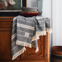 Load image into Gallery viewer, Black/Natural Amana Weave Cotton Throw hanging on sideboard with bowls stacked on top
