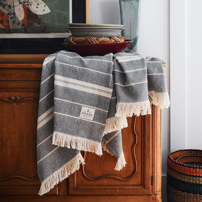 Black/Natural Amana Weave Cotton Throw hanging on sideboard with bowls stacked on top