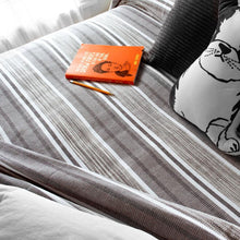 Load image into Gallery viewer, grey Tailrace Cotton Bed Blanket on a bed with a book and pencil
