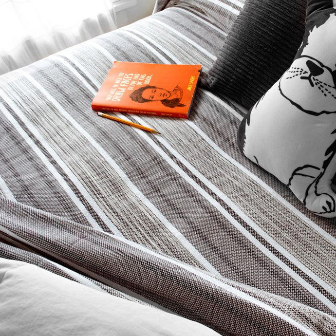 grey Tailrace Cotton Bed Blanket on a bed with a book and pencil